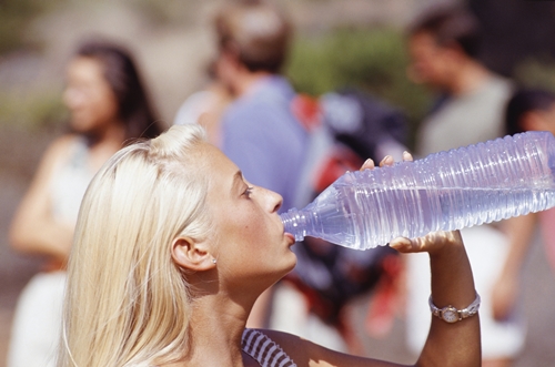 Woman drinking water from bottle, side view